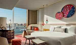 Sovrum med modern inredning och utsikt över en hamn genom fönstret. (AI-genererad text)