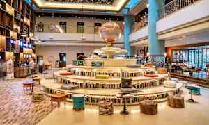 Interiör av ett hotell med bokhylla runt en rund sittplats och dekorativ atmosfär. (AI-genererad text)