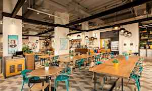 Interiör av en modern restaurang med träbord, färgglada stolar och dekorativa växter. (AI-genererad text)