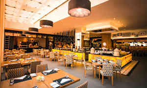 En restaurang med modern inredning, sittgrupper och ett öppet kök. (AI-genererad text)