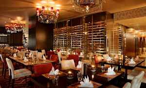 En elegant restaurang med uppdukade bord, vadderade stolar och ljuskronor i taket. (AI-genererad text)