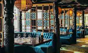 En inredning av en restaurang med turkosa soffor, dekorativa pelare och träpaneler. (AI-genererad text)