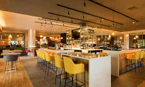 En bar med moderna möbler och en välfylld hylla med flaskor. (AI-genererad text)