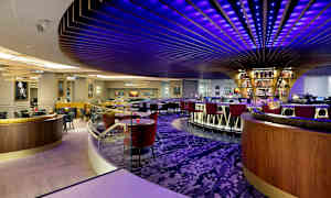 En modern bar med färgglada taklampor och en cirkulär bardisk. (AI-genererad text)