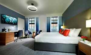 Ett hotellrum med en stor säng, skrivbord och sittmöbler. (AI-genererad text)