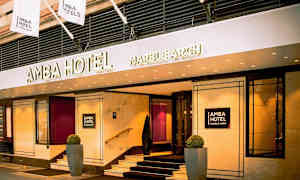 Ingången till Amba Hotel Marble Arch med skyltar och flaggor. (AI-genererad text)