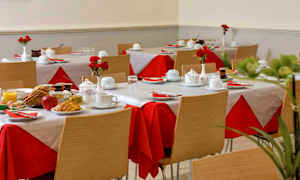 Ett rum med dukade bord, röda och vita dukar, och tallrikar med frukostmat. (AI-genererad text)