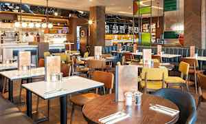 Restaurang med flera matbord och stolar i olika färger. (AI-genererad text)