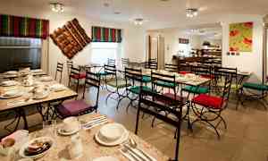 Ett kafé med dukade bord och stolar med färgglada dynor. (AI-genererad text)