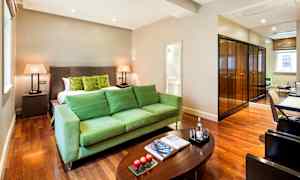 Ett hotellrum med gröna möbler, en stor säng, ett träbord och speglar. (AI-genererad text)