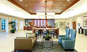 Hotellobby med sittgrupper, bord, växter och receptionsdisk. (AI-genererad text)