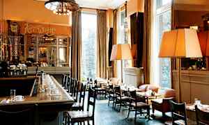 En elegant bistro med bar och bord med dukar, arrangerade vid stora fönster. (AI-genererad text)