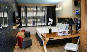 Ett modernt hotellrum med en dubbelsäng, skrivbord och sittgrupp. (AI-genererad text)