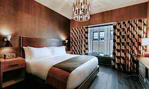 Ett hotellrum med en stor säng, nattduksbord, fönster med gardiner och ett skrivbord bredvid. (AI-genererad text)