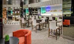 Interiör av en modern bar med höga stolar vid runda bord och en bardisk i bakgrunden. (AI-genererad text)