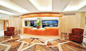 En lobbyinteriör med en receptionsdisk, sittplatser och ett marmorgolv. (AI-genererad text)