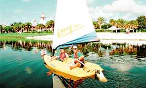 En segelbåt på en sjö med en strand och gröna träd i bakgrunden. (AI-genererad text)