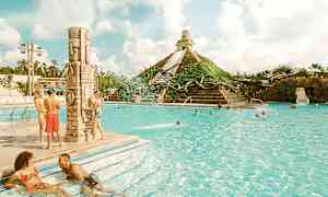 Bilden visar en utomhuspool med människor som njuter av vattnet och en pyramidformad vattenattraktion i bakgrunden. (AI-genererad text)