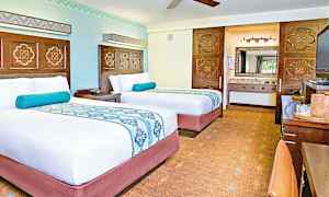 Två välbäddade sängar i ett hotellrum med ljusa väggar och dekorativa element. (AI-genererad text)