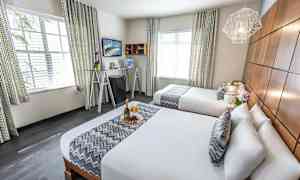 Ett hotellrum med två dubbelsängar, elegant inredning och dekorativa detaljer. (AI-genererad text)