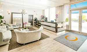 En hotellobby med ljusa soffor, ett receptionsområde samt ett bord dekorerat med orkidéer. (AI-genererad text)