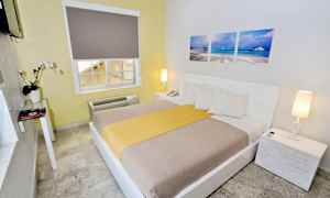 Ett hotellrum med en dubbelsäng, vit inredning och dekorationer. (AI-genererad text)