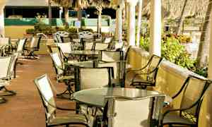 Utomhusområde med bord och stolar för sittplatser, omgiven av vegetation. (AI-genererad text)