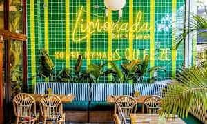 Restauranginteriör med grönt kaklat väggytor, neonskyltar, palmer, träbord och flätade stolar. (AI-genererad text)