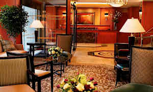 Ett smakfullt inrett hotellobbyområde med möblerade sittplatser, inredningsdetaljer, blomsterarrangemang och reception i bakgrunden. (AI-genererad text)