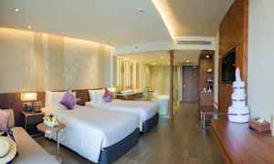 Ett hotellrum med två enkelsängar, en sittgrupp, och ett badrum med glasväggar. (AI-genererad text)