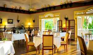 Interiör av en elegant restaurang med bord täckta med vita dukar, trästolar och dekorativa element på väggarna. (AI-genererad text)