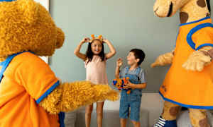 Två barn interagerar med en björn- och giraffmaskot och verkar ha kul. (AI-genererad text)