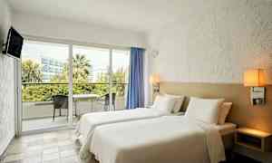 Hotellrum med två enkelsängar och en balkong med möbler. (AI-genererad text)