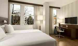 Hotellrum med två enkelsängar, skrivbord, stol och TV. (AI-genererad text)