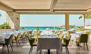 Restaurang med dukade bord och utsikt mot havet. (AI-genererad text)