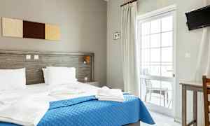 Ett hotellrum med en dubbelsäng, blå överkast och vita sängkläder. (AI-genererad text)