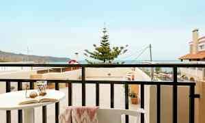 En balkong med utsikt mot havet och närliggande byggnader. (AI-genererad text)