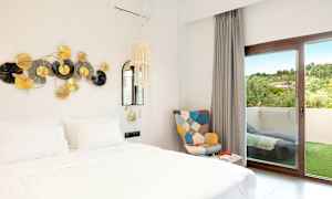 Bild på ett hotellrum med en vit säng, dekor på väggen och en dörr till en balkong. (AI-genererad text)