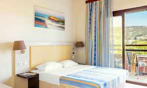 Ett hotellrum med en säng, upplyst med naturligt ljus från en balkong. (AI-genererad text)