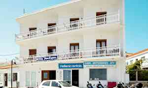 Vit byggnad med skyltar för hotell och uthyrning av fordon. Mopeder och en bil är parkerade framför. (AI-genererad text)