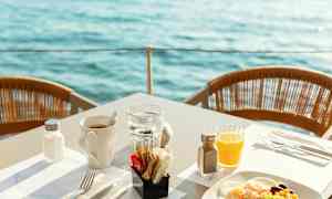 Frukost serverad vid bord med utsikt över vattnet. (AI-genererad text)