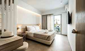 Ett hotellrum med en dubbelsäng, en tv och en balkongdörr. Skrivbord med hatt och stol. (AI-genererad text)