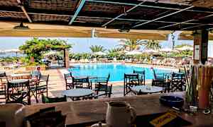 En uteservering med utsikt över en pool och solstolar under parasoller. (AI-genererad text)