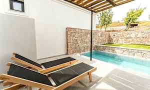 Två solstolar vid en liten pool bredvid en stenmur. (AI-genererad text)