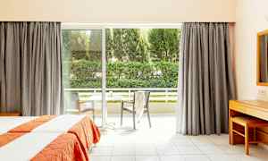 Hotellrum med två enkelsängar och stor fönsterdörr som leder ut till en balkong. (AI-genererad text)