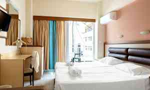 Hotellrum med dubbelsäng och skrivbord, samt balkong med utsikt. (AI-genererad text)