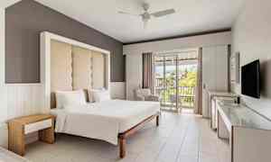 Hotellrum med en dubbelsäng, modern inredning och en balkong med utsikt. (AI-genererad text)