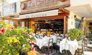 En restaurang med uteservering dekorerad med vita dukar och blomstrande växter. (AI-genererad text)