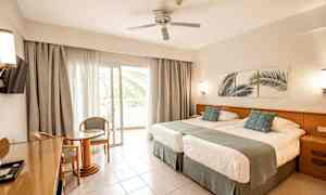 Hotellrum med två sängar, sittgrupp och balkong. (AI-genererad text)