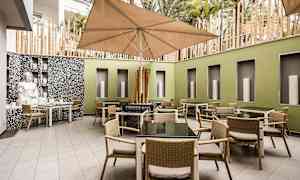 Innergård med bord och stolar samt en stor parasoll. (AI-genererad text)